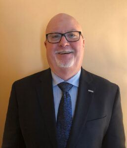 bald man posing for headshot wearing glasses and business attire 