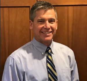 man posing for headshot wearing a button-up shirt and tie